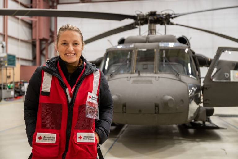 Woman in Red Cross vest in front of a helicopter