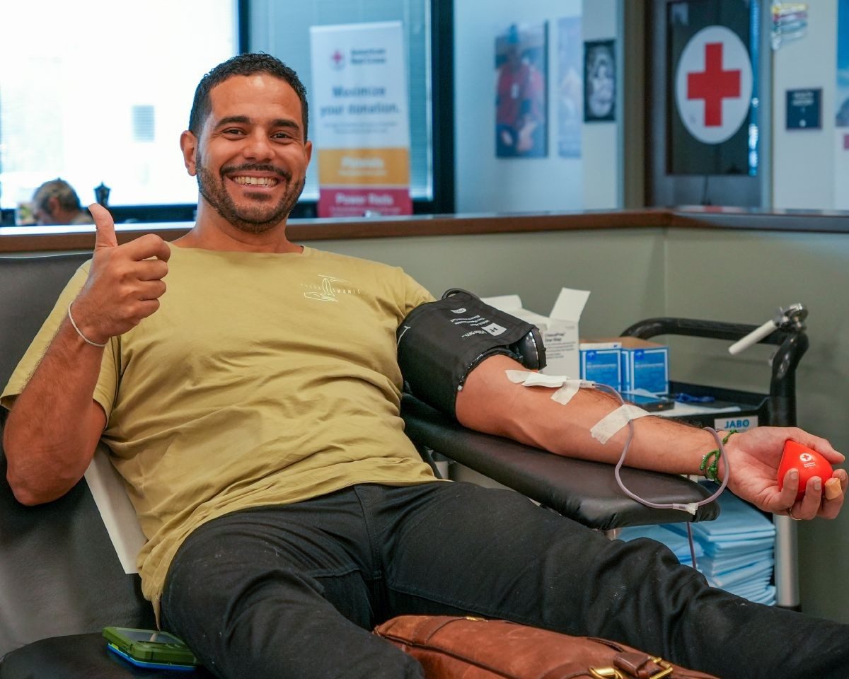 Smiling man sitting in a chair giving blood.