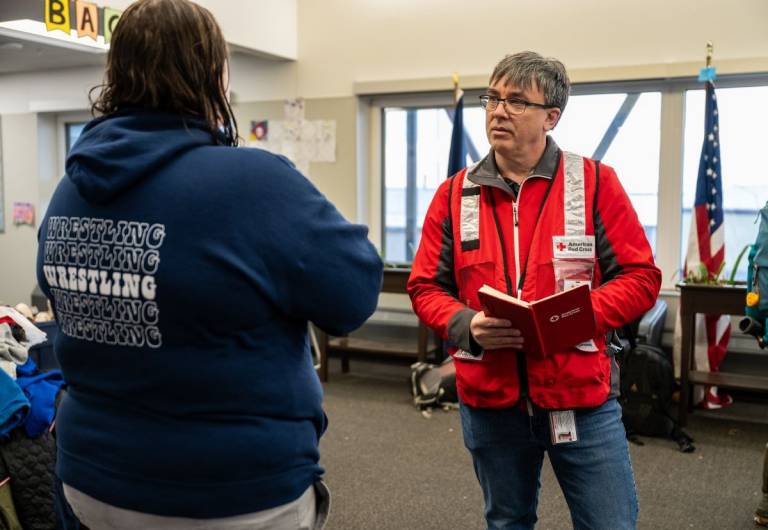 man in Red Cross vest talks with another man in Alaska