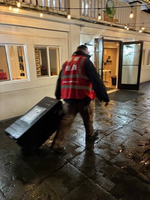 Man in Red Cross vest moves totes carrying shelter supplies