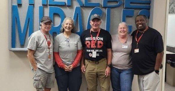 group of people, some wearing Red Cross badges, stand together