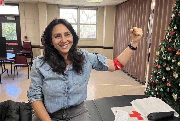 Ana Maria is at a Red Cross donation center, smiling and pumping her fist after her first blood donation.