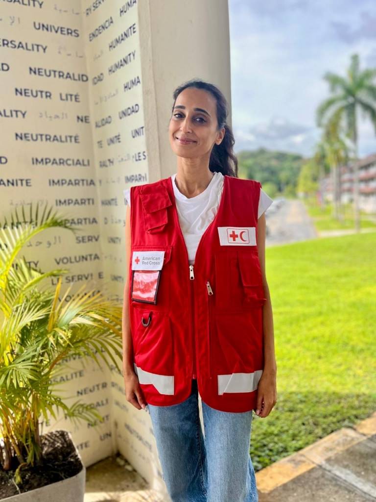 Woman standing, wearing Red Cross vest.