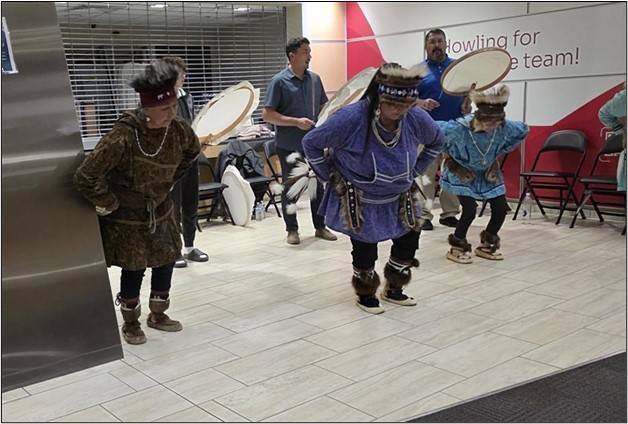 Men in native Alaskan dress perform a traditional dance
