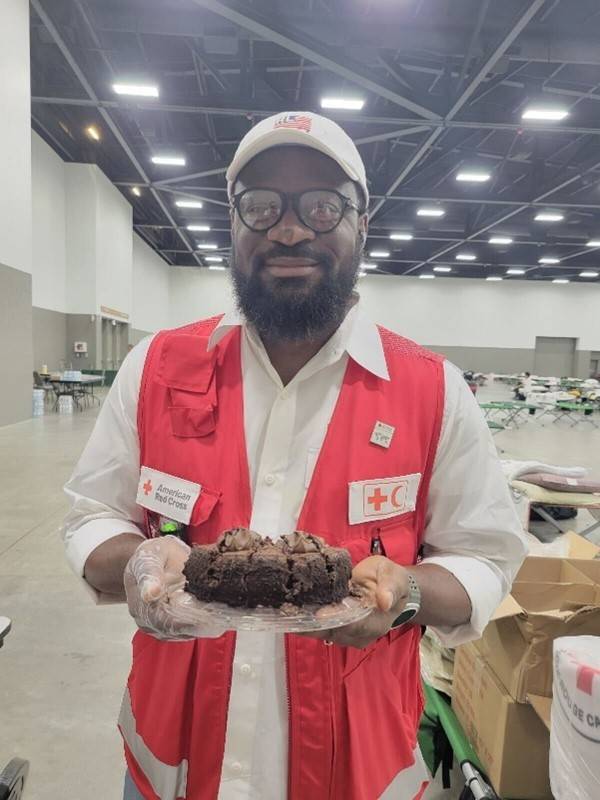 Man in Red Cross vest holding a cake