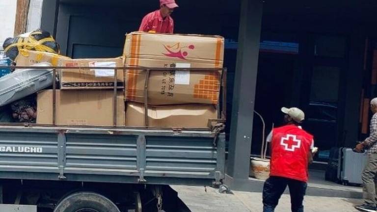 Personas con chalecos de la Cruz Roja descargan suministros de un camión.