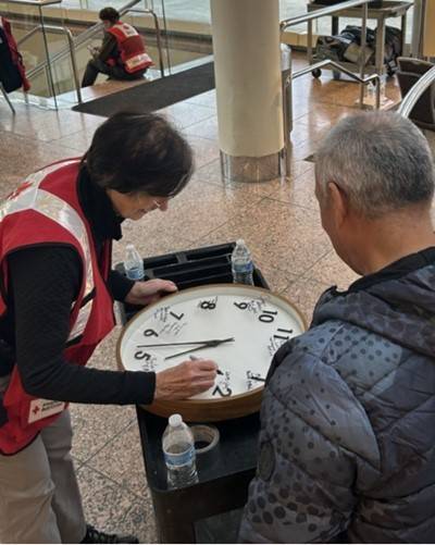 Woman holds wall clock as man looks on.