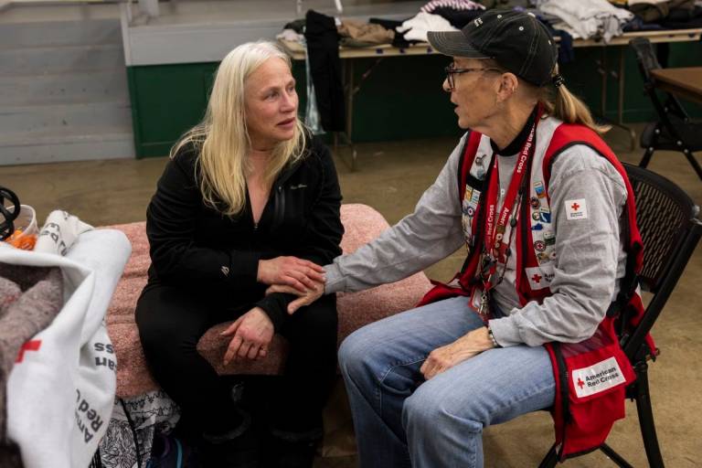 Red Cross volunteer talks with another woman in a shelter