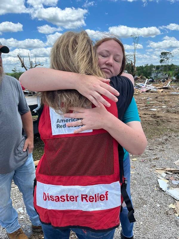  two woman hug, one in a Red Cross vest