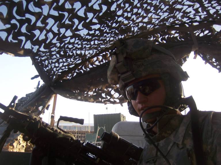 Kyle sits in a machine gun nest with combat gear.