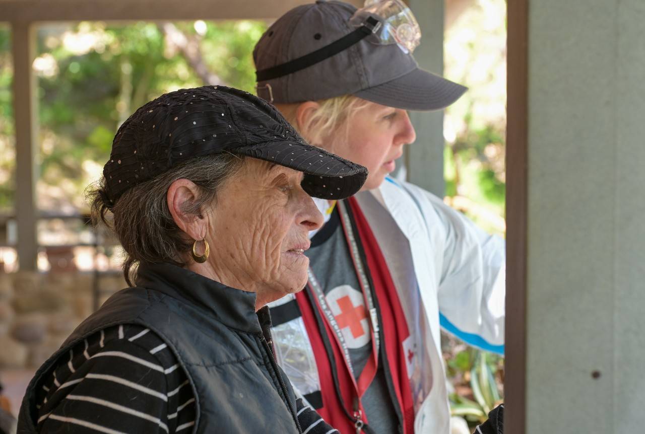 Two women, one older wearing black baseball cap, one younger wearing gray baseball cap