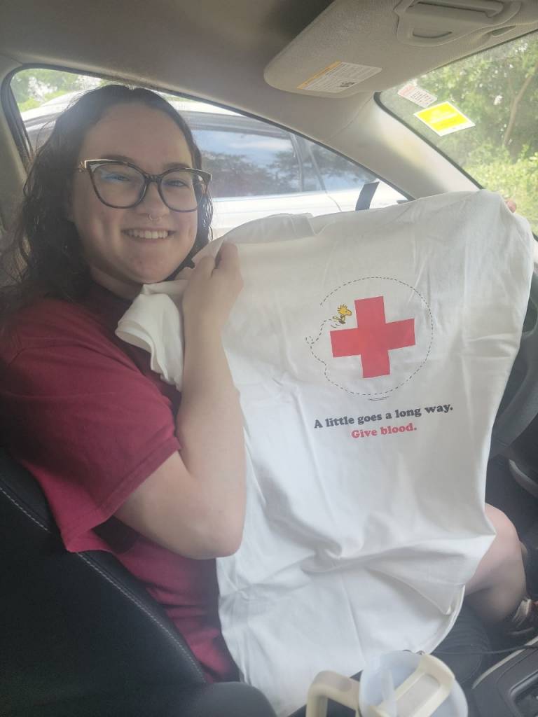 Woman holding up a Peanuts tee shirt