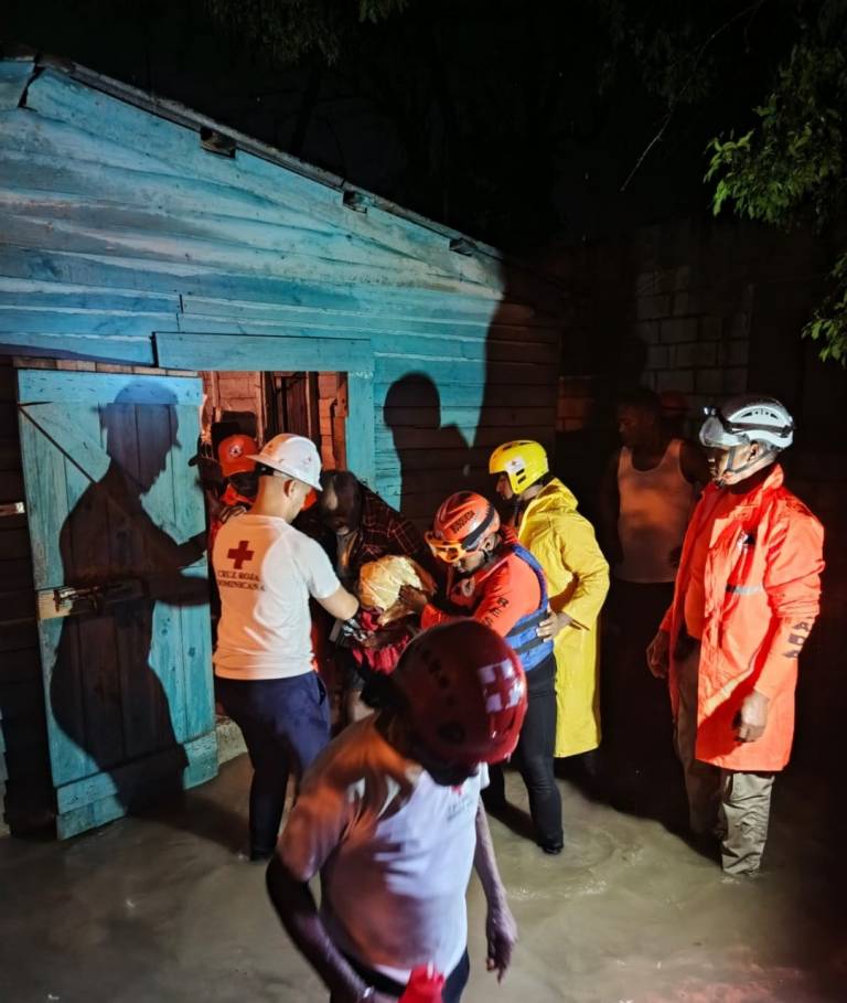 men in Red Cross clothing help evacuate someone