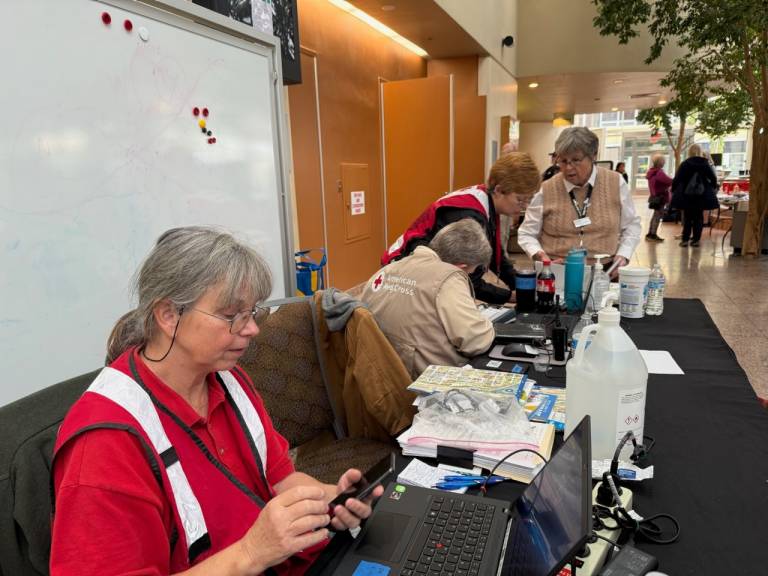 Women in Red Cross vests work at a table in a shelter