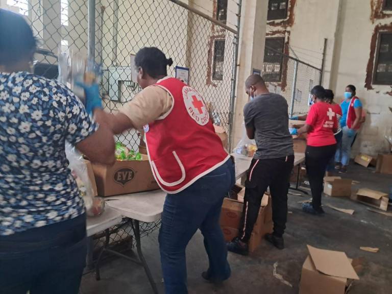 people in Red Cross vests prepare relief supplies