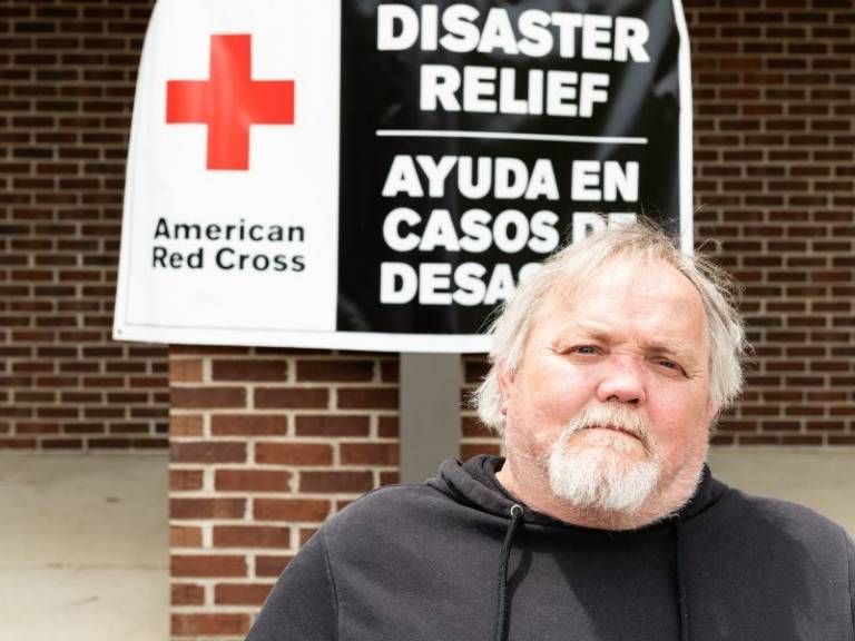 Man sits outside a Red Cross disaster shelter