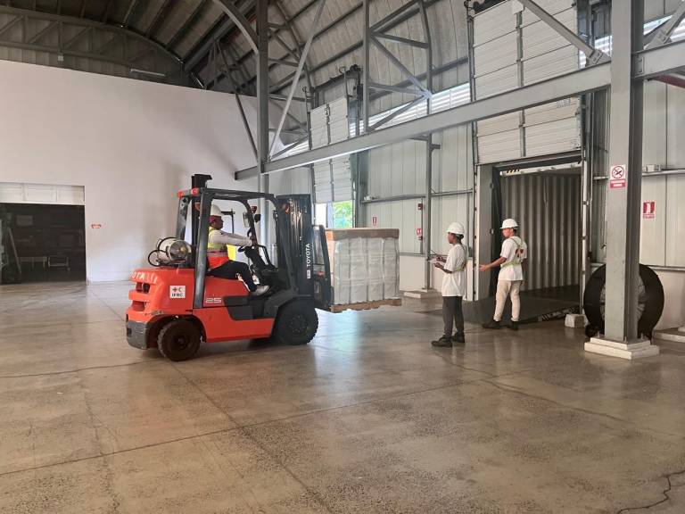 Red Cross personnel in a warehouse moving supplies with a forklift
