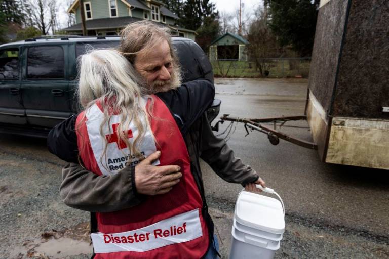 Man hugging woman in Red Cross vest