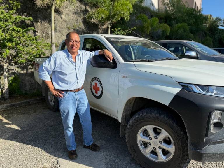 Man stands next to a white Red Cross truck. 