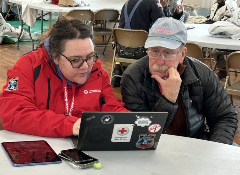 Two Red Cross disaster responders talk over a computer to plan opening a shelter.