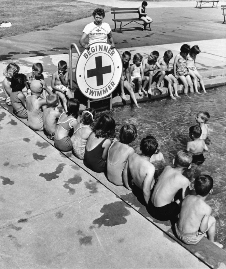 – In historical photo, swimmers lined up in the pool for a swimming lesson