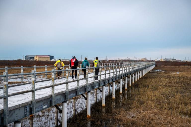 man in Red Cross vest walks on Alaska boardwalk