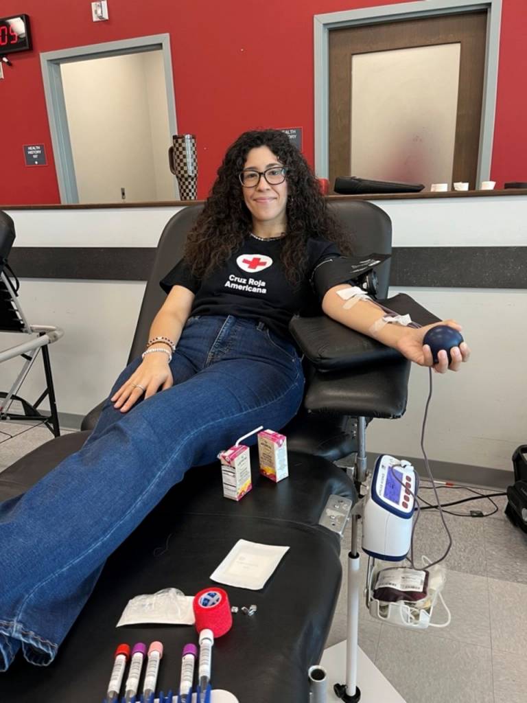 Person sitting in a blood donation chair and donating blood.