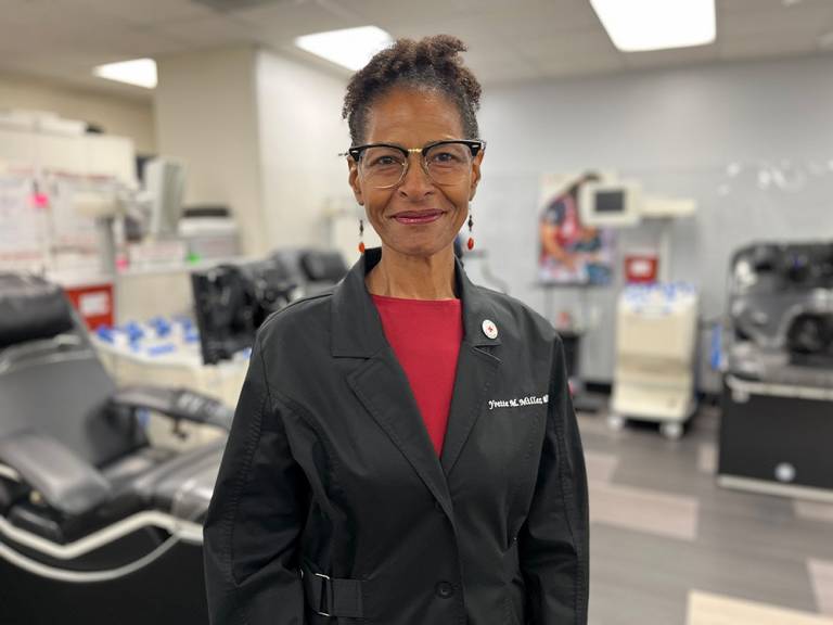Photo of Dr. Yvette Miller, Red Cross executive medical officer, in a blood donation center wearing a black medical coat.