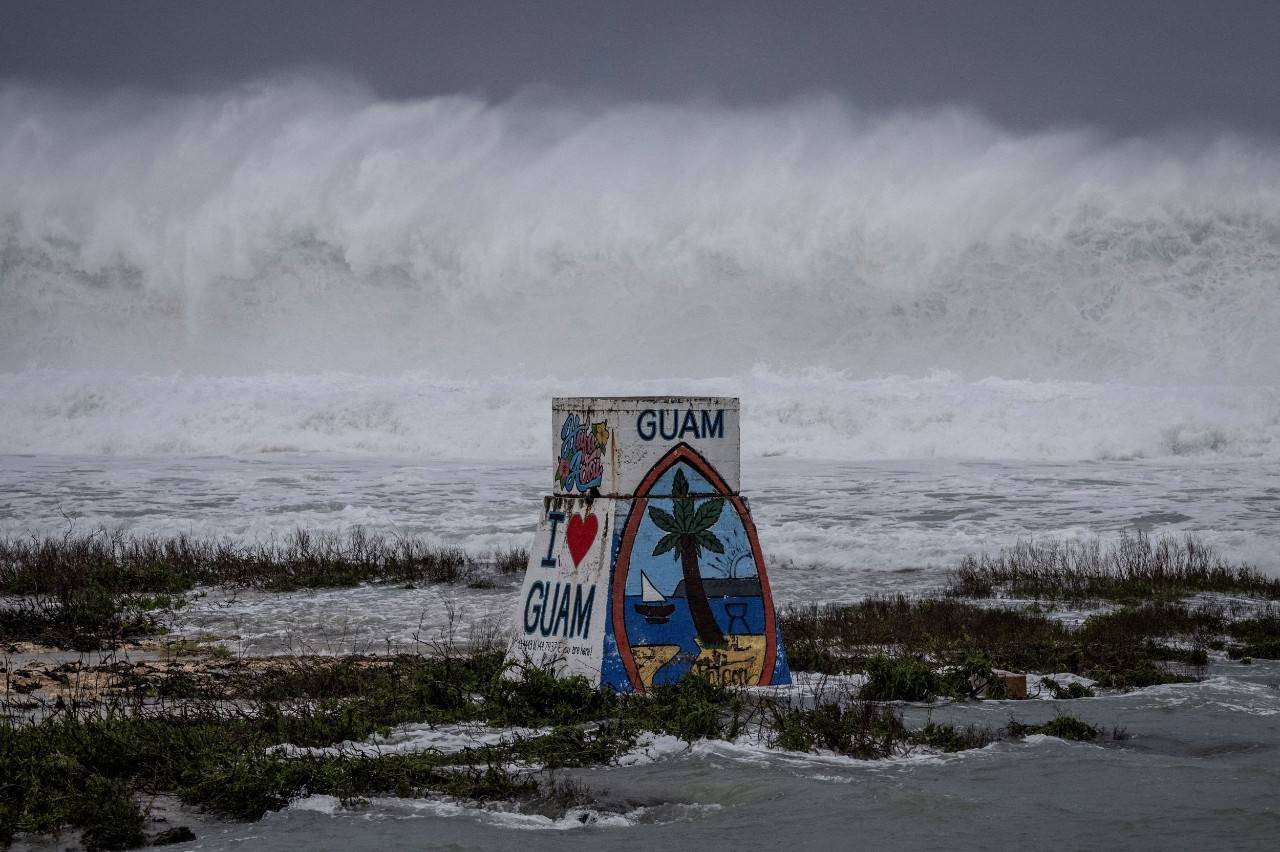 Large buoy that says Guam near the ocean.
