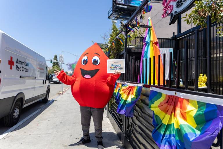 Mascot Buddy the Blood Drop stands outside a Gossip Grill Blood Drive.