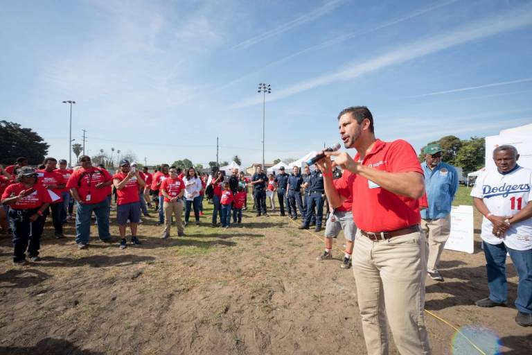 man in Red Cross shirt speaks to crowd of Red Cross volunteers