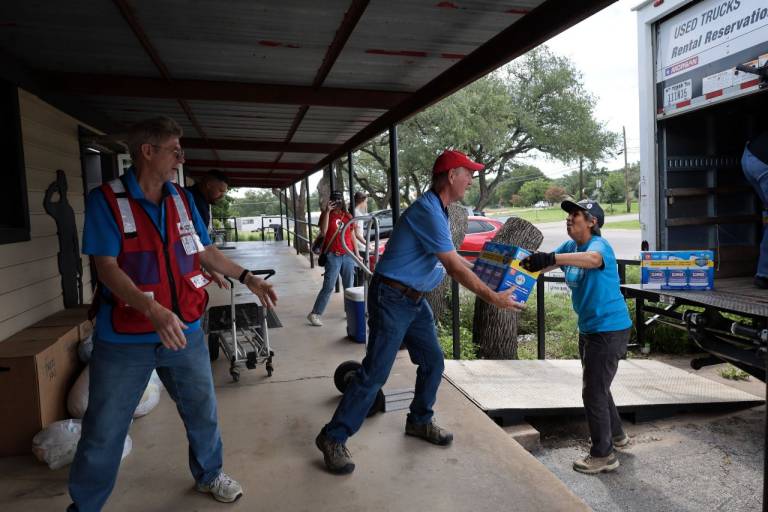 People in Red Cross tee shirts unload a large truck.