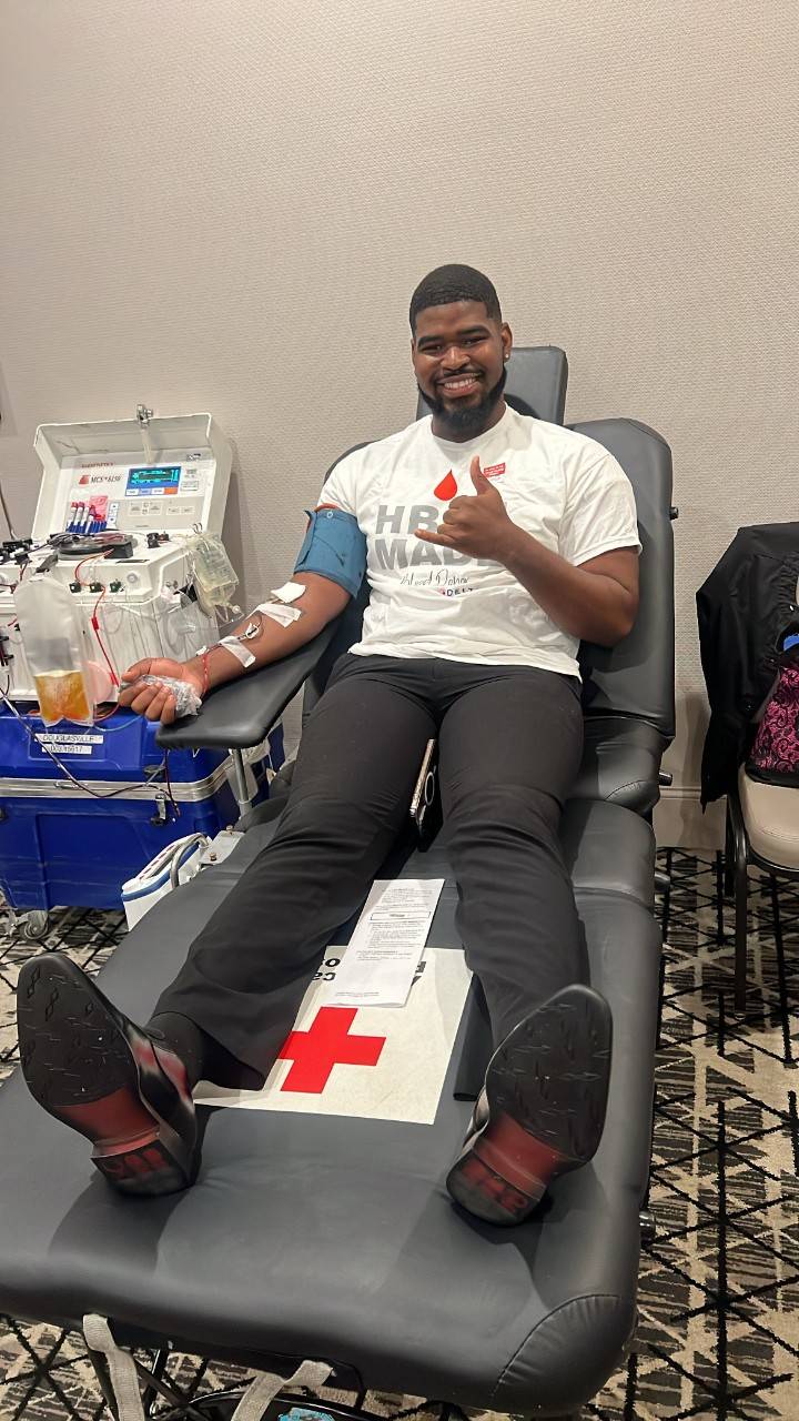 Michael C. Prescot, Jr. donating Power Red while seated at a blood drive, connected to an automated red cell collection machine.