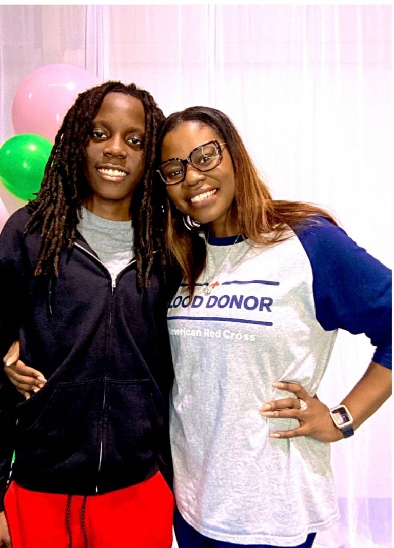 A mother and her son stand and smile together