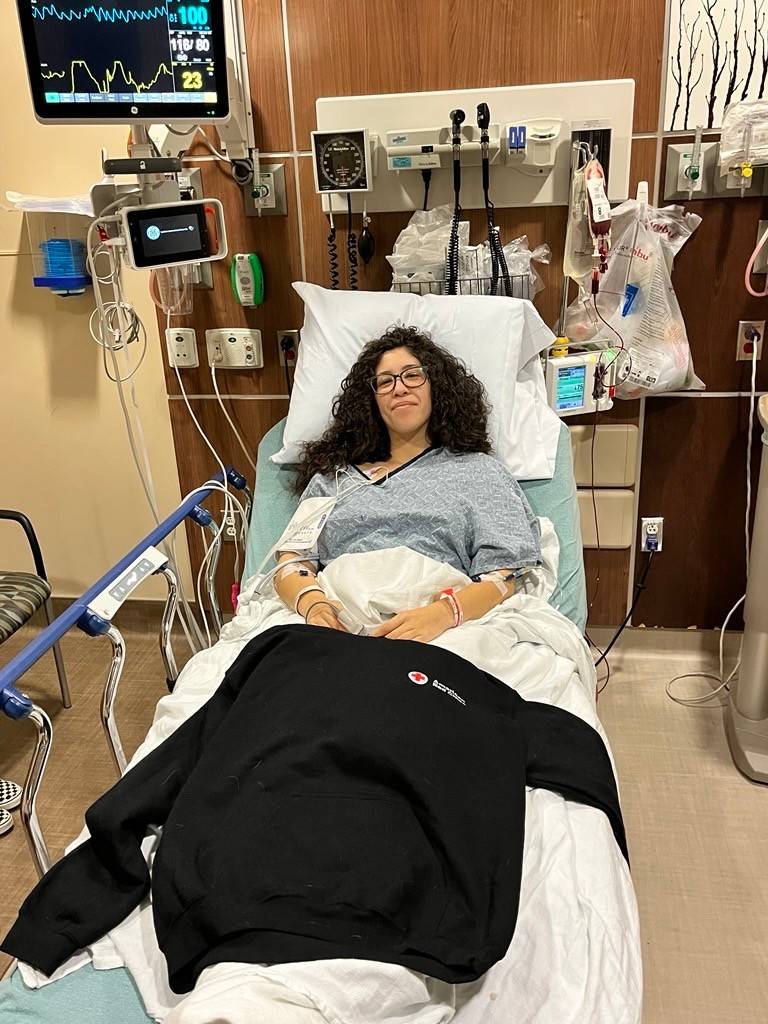 Mujer echada en una cama de hospital conectada a distintos aparatos médicos