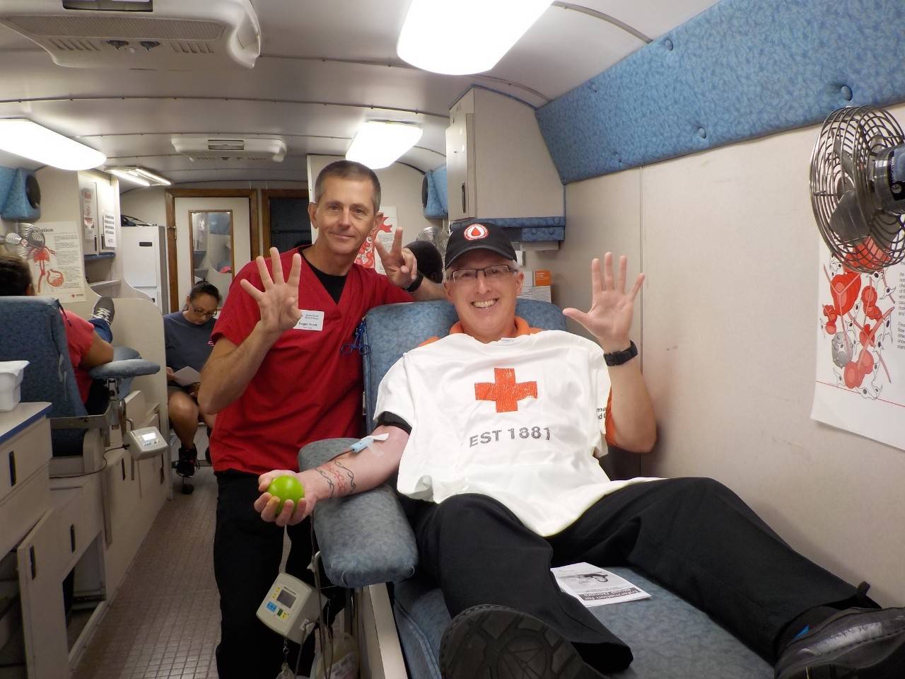 Man in Red Cross baseball hat on blood donor bed