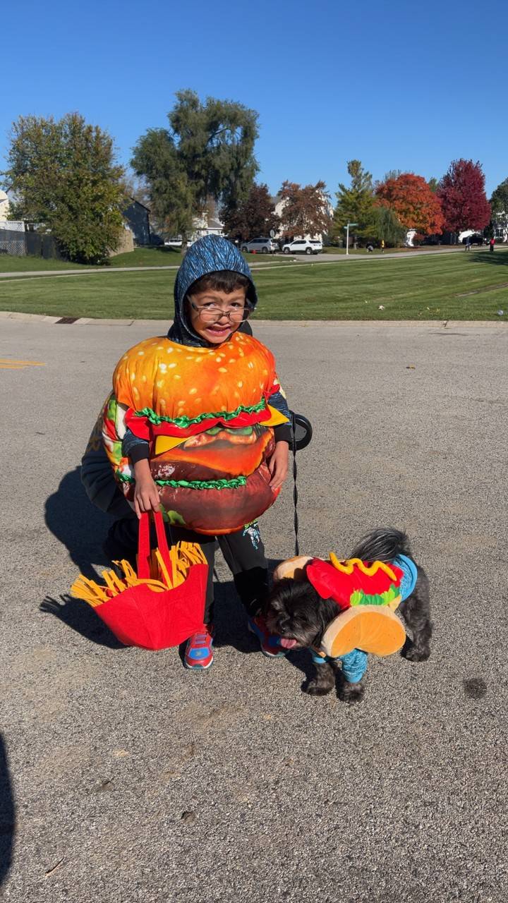 Young boy in hamburger costume with a dog.