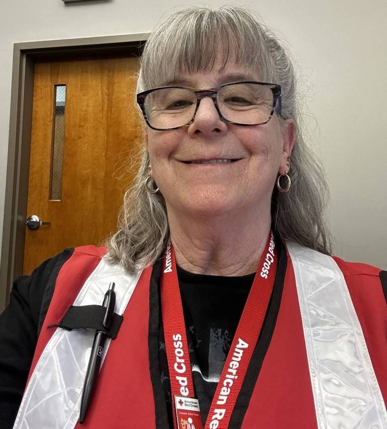 Woman with big glasses, wearing Red Cross clothing.