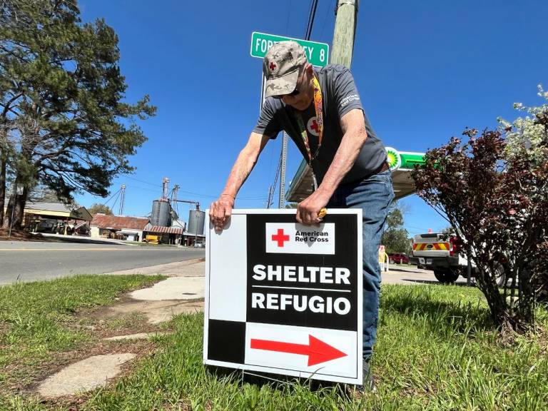 Un hombre coloca un cartel de un refugio de la Cruz Roja Americana