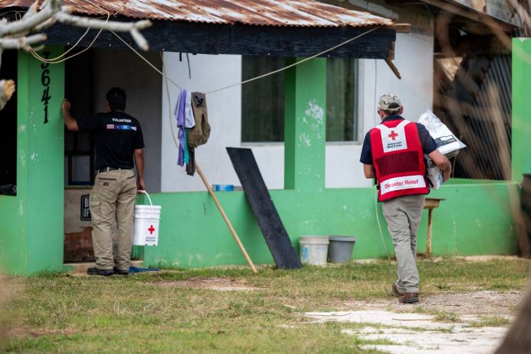 Two men in Red Cross shirts deliver supplies to a home on Saipan.