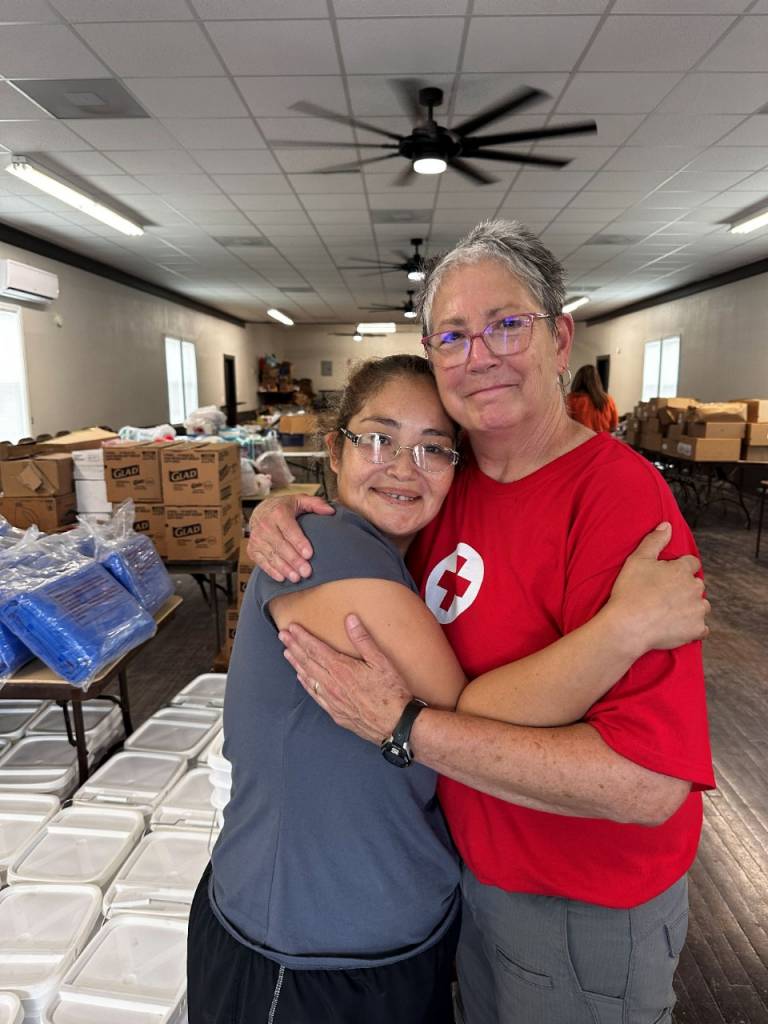 Two women, one in a Red Cross tee shirt, embrace