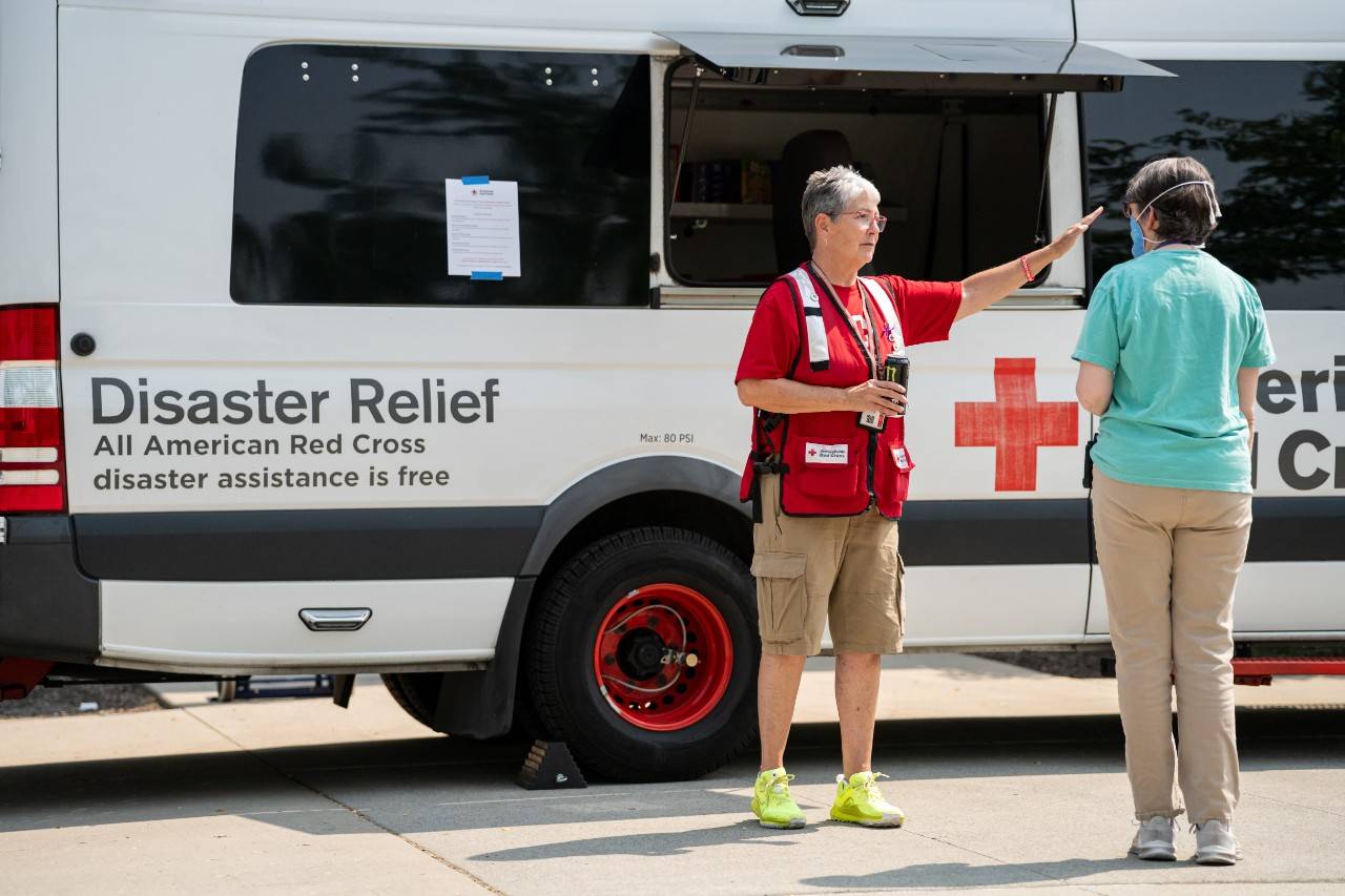 August 6, 2026. Spokane, Washington.Red Cross volunteer Kathryn Wescott talks with a local resident about unmet needs and directs her towards the Disaster Assistance Center, where the Red Cross offered on-site health and mental health support and shared information about other available resources from the Red Cross such as safe shelter and emergency supplies. Kathryn, a Red Cross volunteer from Grand Junction, CO, enjoys helping people, saying  This is the best part of being a volunteer, meeting people and helping them. I m glad I can be here and help. Photo by Jason Colston/American Red Cross