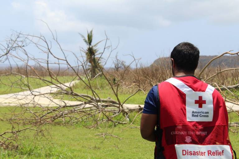 man in Red Cross vest walks down street