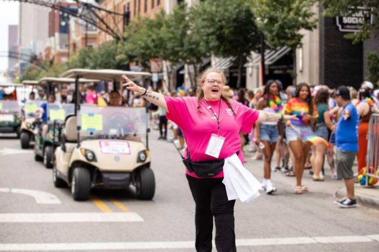 Cass Helm marches proudly down the street during a public event with arms wide open, showing a sign of welcome for all. 