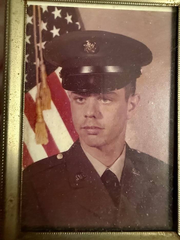 Military headshot of man with American flag behind him