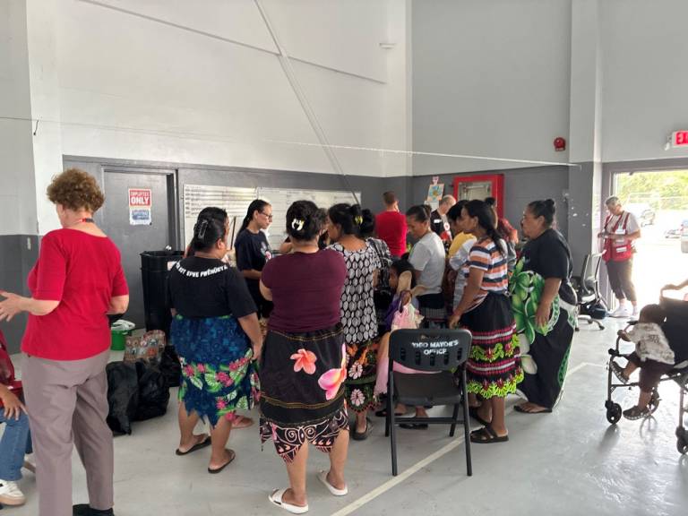 A group of women stand and listen as Red Cross volunteer explains the latest information after the typhoon.