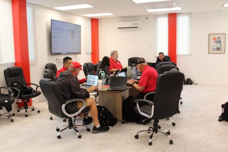 People gather around table in Red Cross clothing