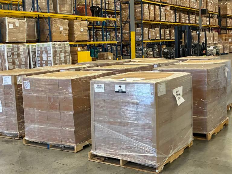 Pallets of relief supplies are stacked up in a large warehouse