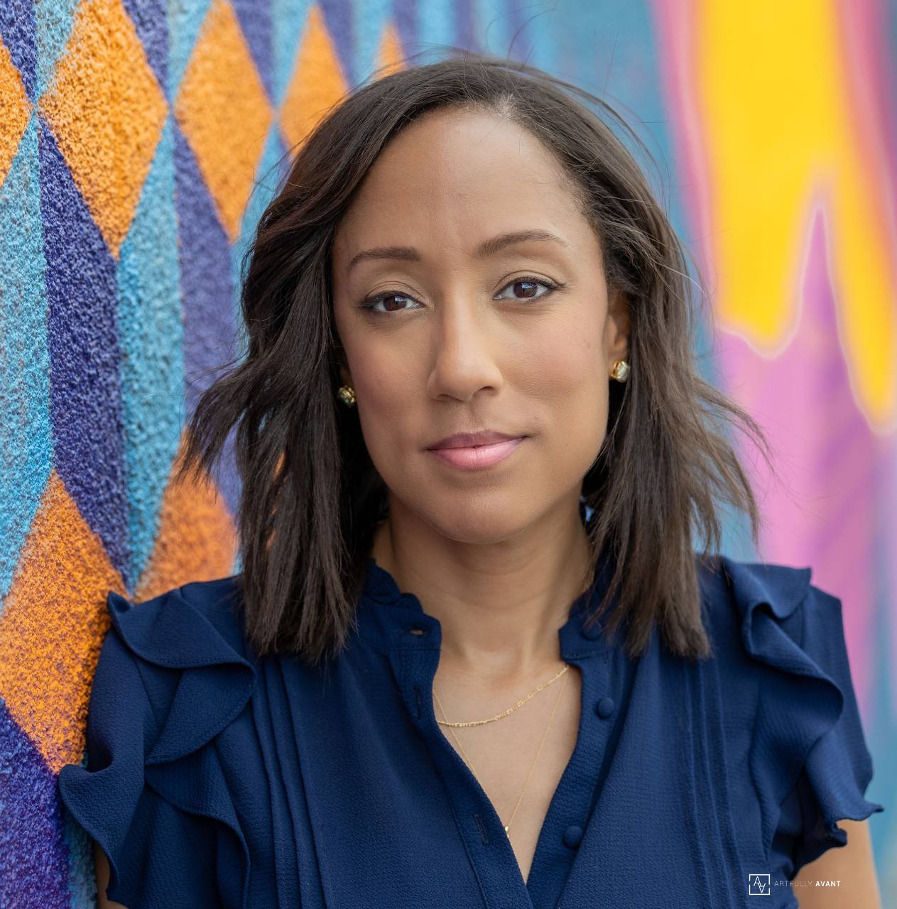 Heather Avant smiling in a professional portrait against a colorful background. 