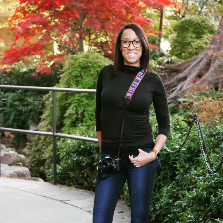 Heather Avant standing with her camera, outdoors.